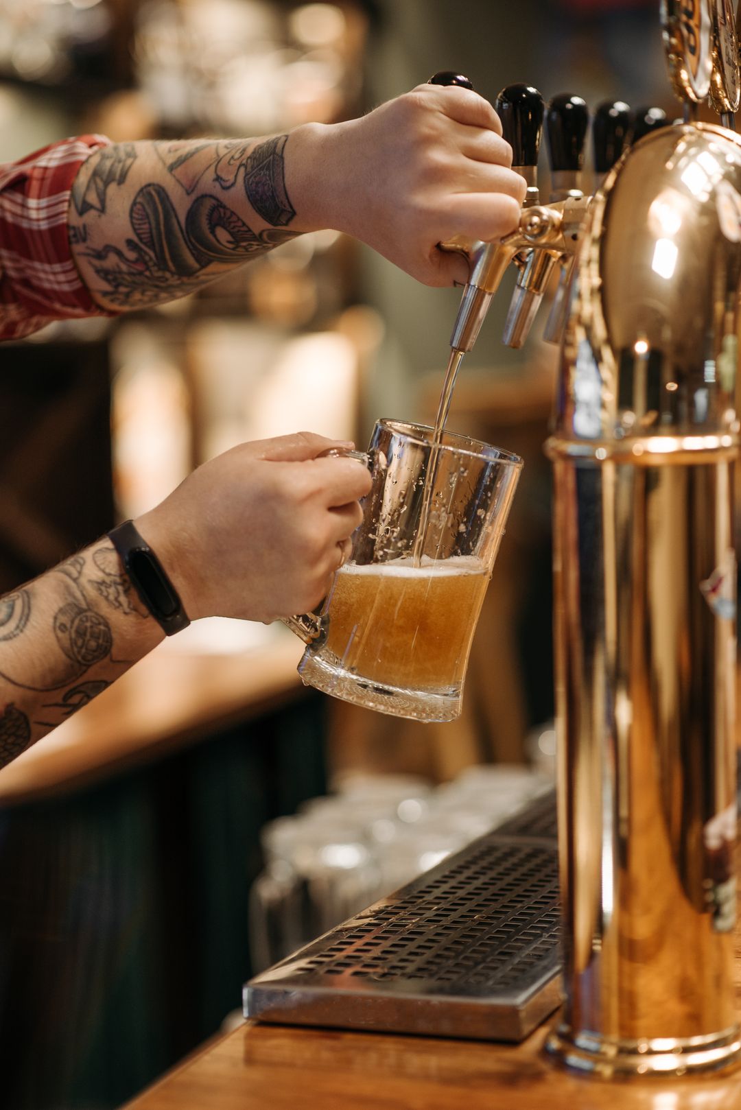 Bartender pouring a pint from a brass tap