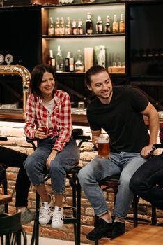 Two friends enjoying drinks at a pub, smiling and bonding over a beer.