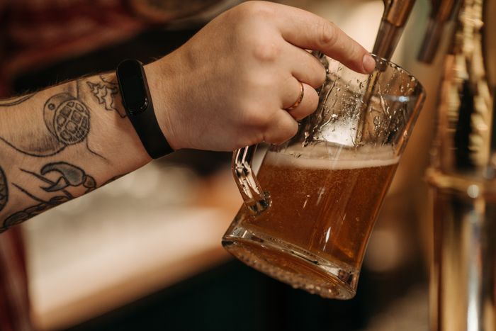 Hand holding a foaming glass mug of golden ale