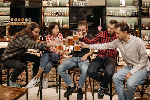 People Toasting their Mugs with Beer