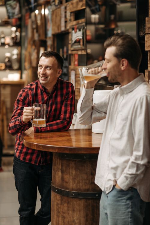 Free Two men enjoy a relaxed conversation over beers in a cozy pub setting. Stock Photo