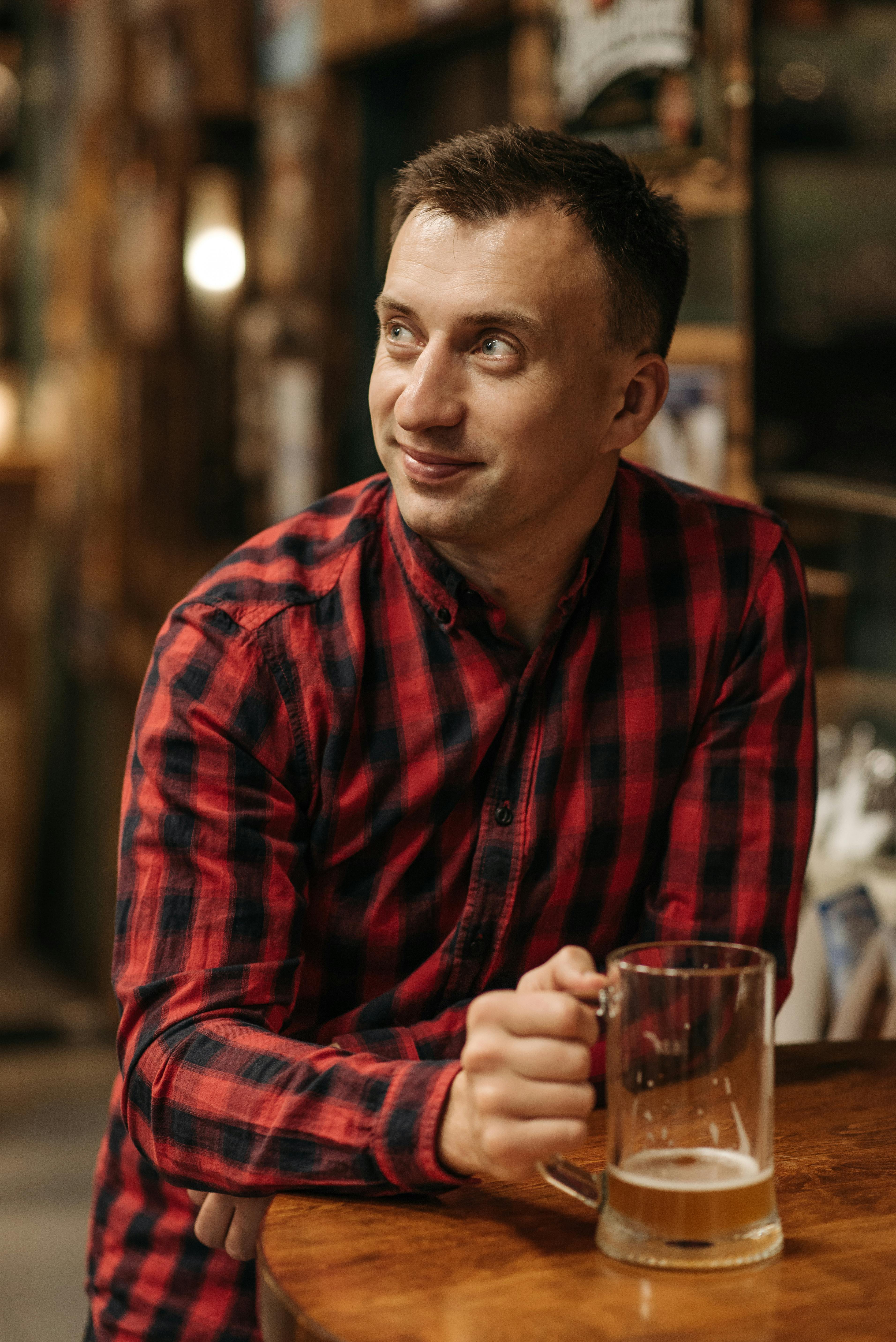 man in checkered long sleeve shirt holding a beer glass