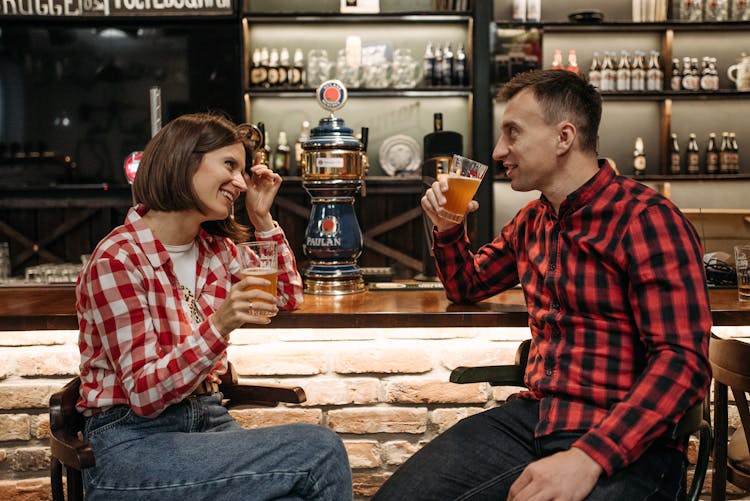 Man And Woman Sitting On Chairs At The Bar