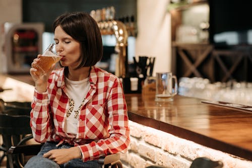 Free A Woman in Plaid Long Sleeves Drinking Beer Stock Photo
