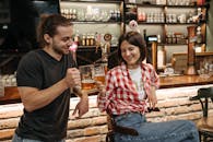 Man in Black Crew Neck T-shirt Holding Drinking Glass Beside Woman in Red and White