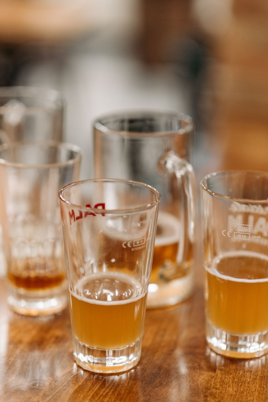 Close-up of half-filled beer glasses on a wooden table, capturing a casual drinking setting.