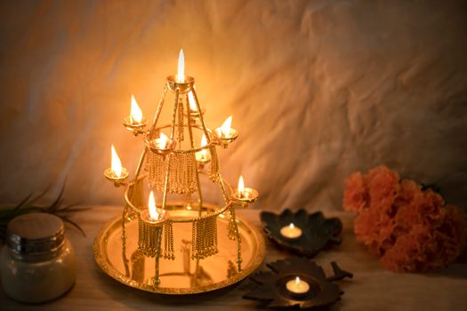 Intricate brass candle holder with lit candles, surrounded by flowers, creating a warm festive ambiance.