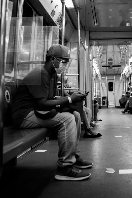 Grayscale Photo of a Man Using His Cellphone in the Train