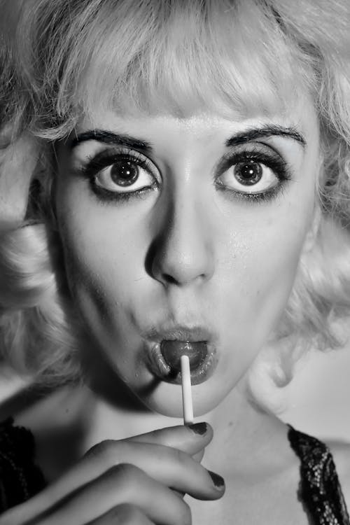 Grayscale Photo of a Woman with a Lollipop in Her Mouth