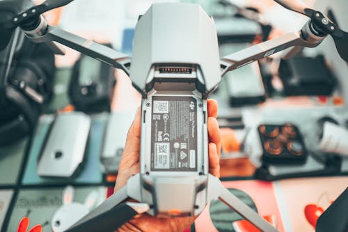 Top view of crop anonymous camera man showing drone with propellers at home in soft daylight