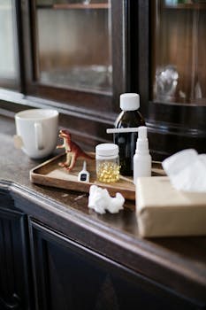 A set of medicine bottles, a toy dinosaur, and personal items arranged on a wooden tray indoors.
