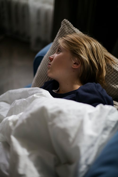 Girl in Blue Shirt Lying on Brown Sofa