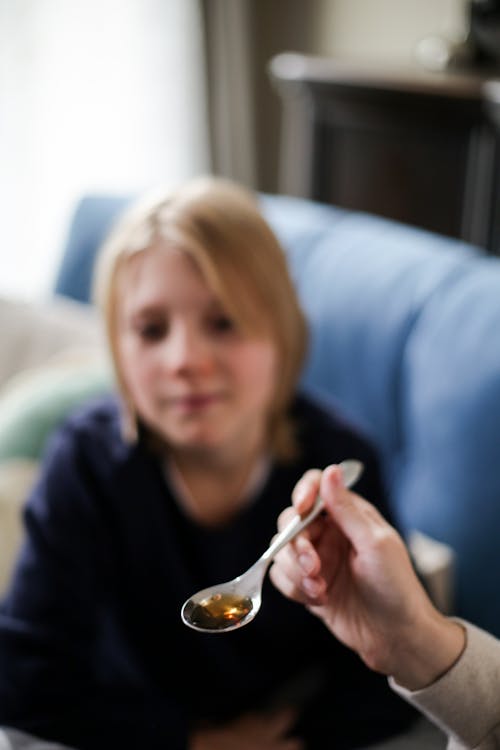 Free A Person Holding a Spoon with Cough Syrup Stock Photo