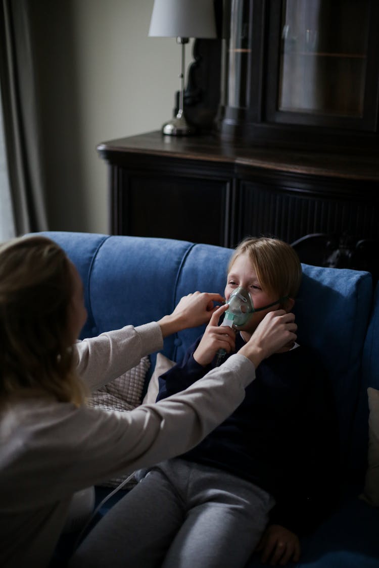 A Sick Boy In Blue Long Sleeves Sitting On The Couch