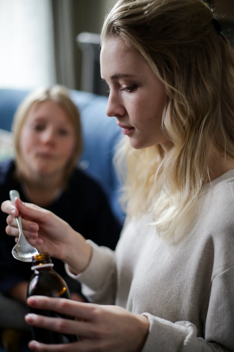 A Woman Holding A Spoon With Cough Syrup