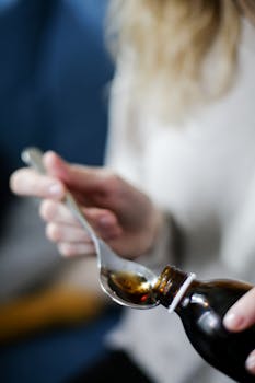 Close-up of hand pouring cough syrup into a spoon, perfect for healthcare concepts.