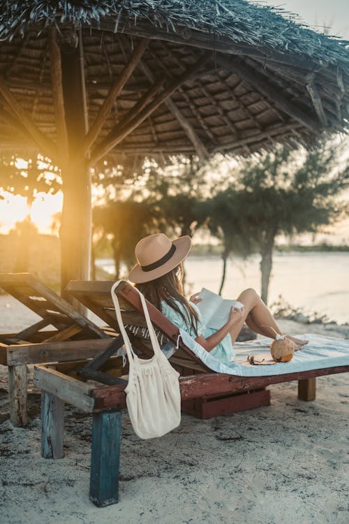 A Woman Lying on a Sun Lounger while Reading a Book