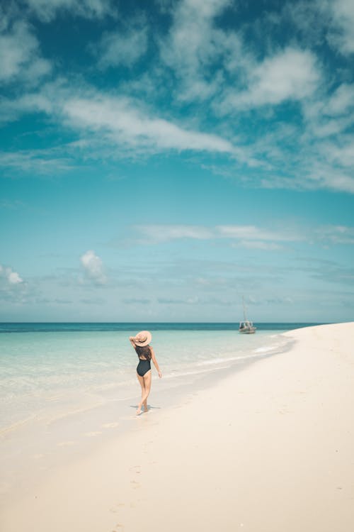Free Photo of a Woman in a Black Swimsuit Walking on the Seashore Stock Photo
