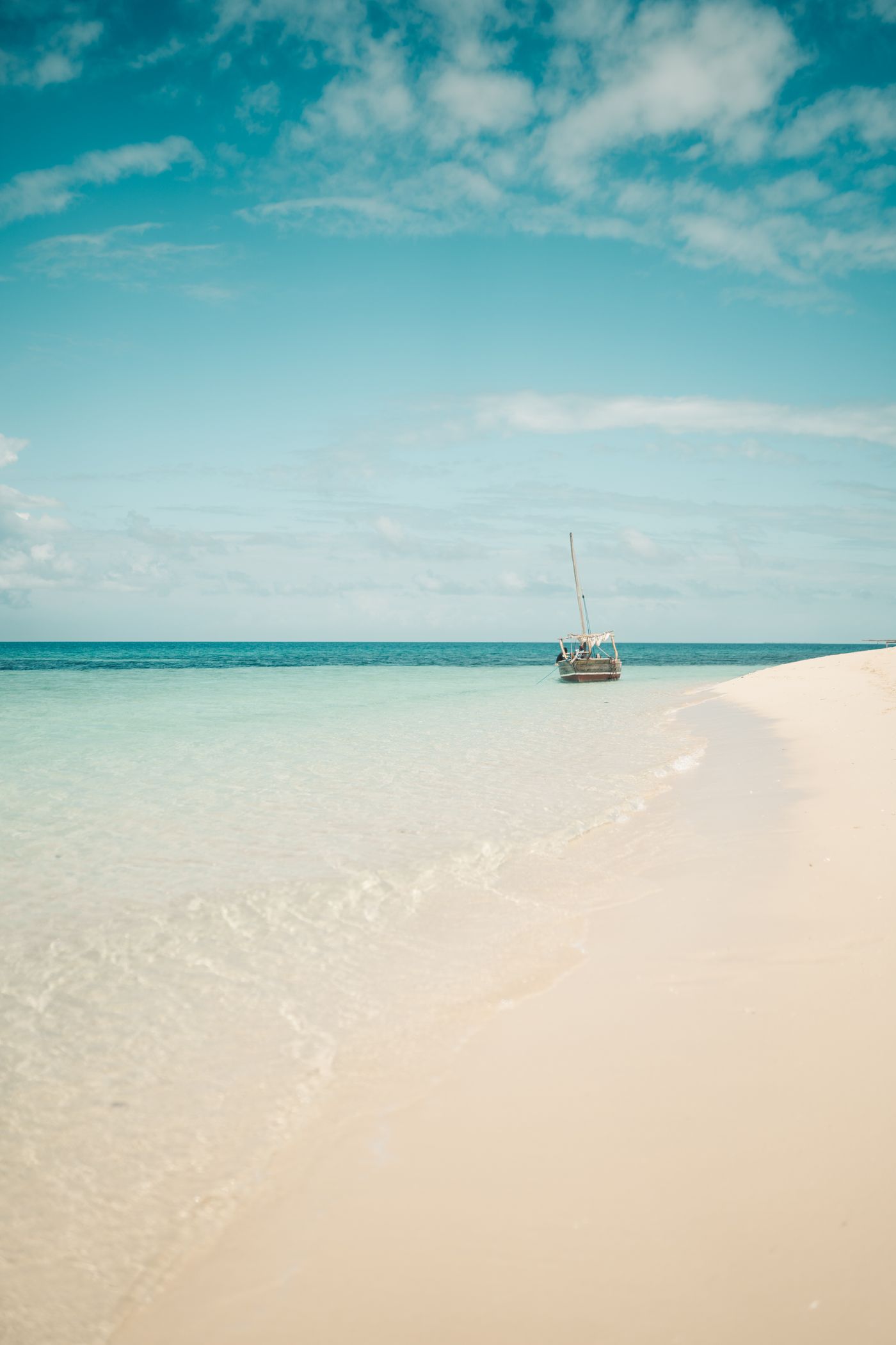 A traditional dhow resting on white sand