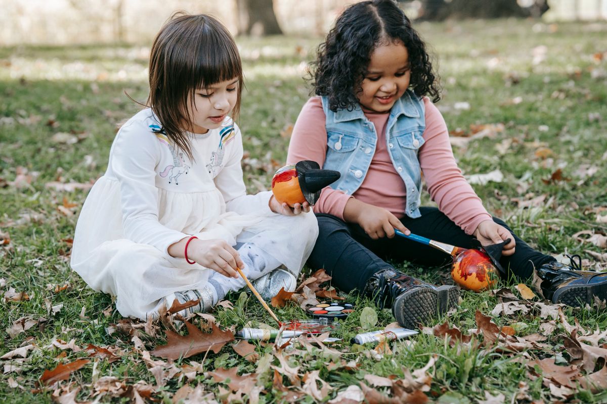 Little girls decorating small pumpkins for Halloween