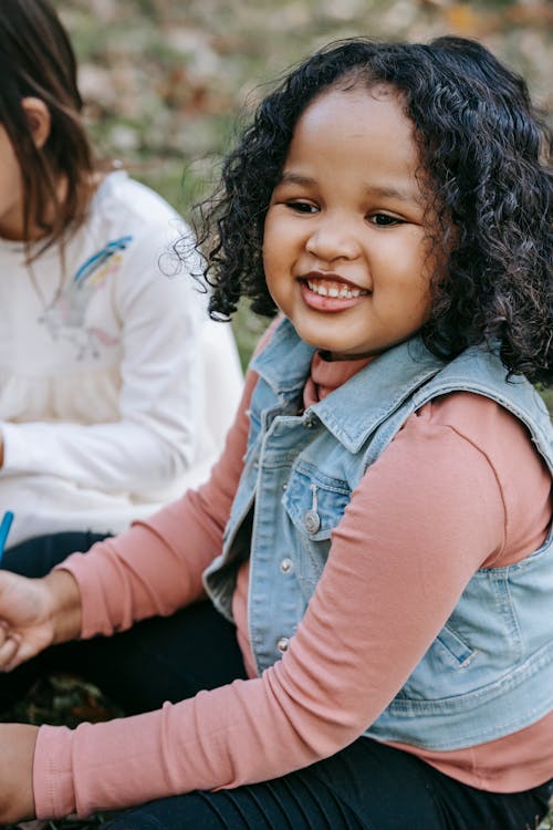 Cheerful black girl sitting in park with friend