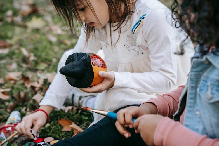 Focused Diverse Girls Painting Pumpkins For Halloween