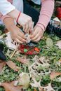 Crop anonymous multiethnic friends preparing acrylic paints for painting sitting together on grass in park