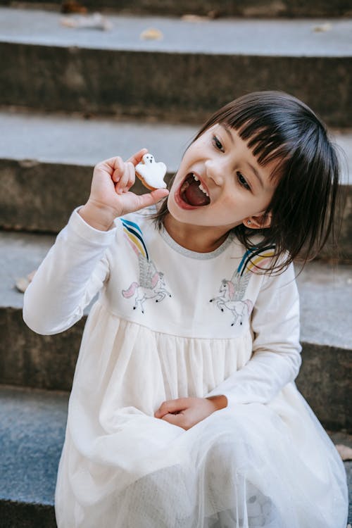 Gadis Ekspresif Lucu Dengan Mulut Terbuka Menunjukkan Kue Hantu