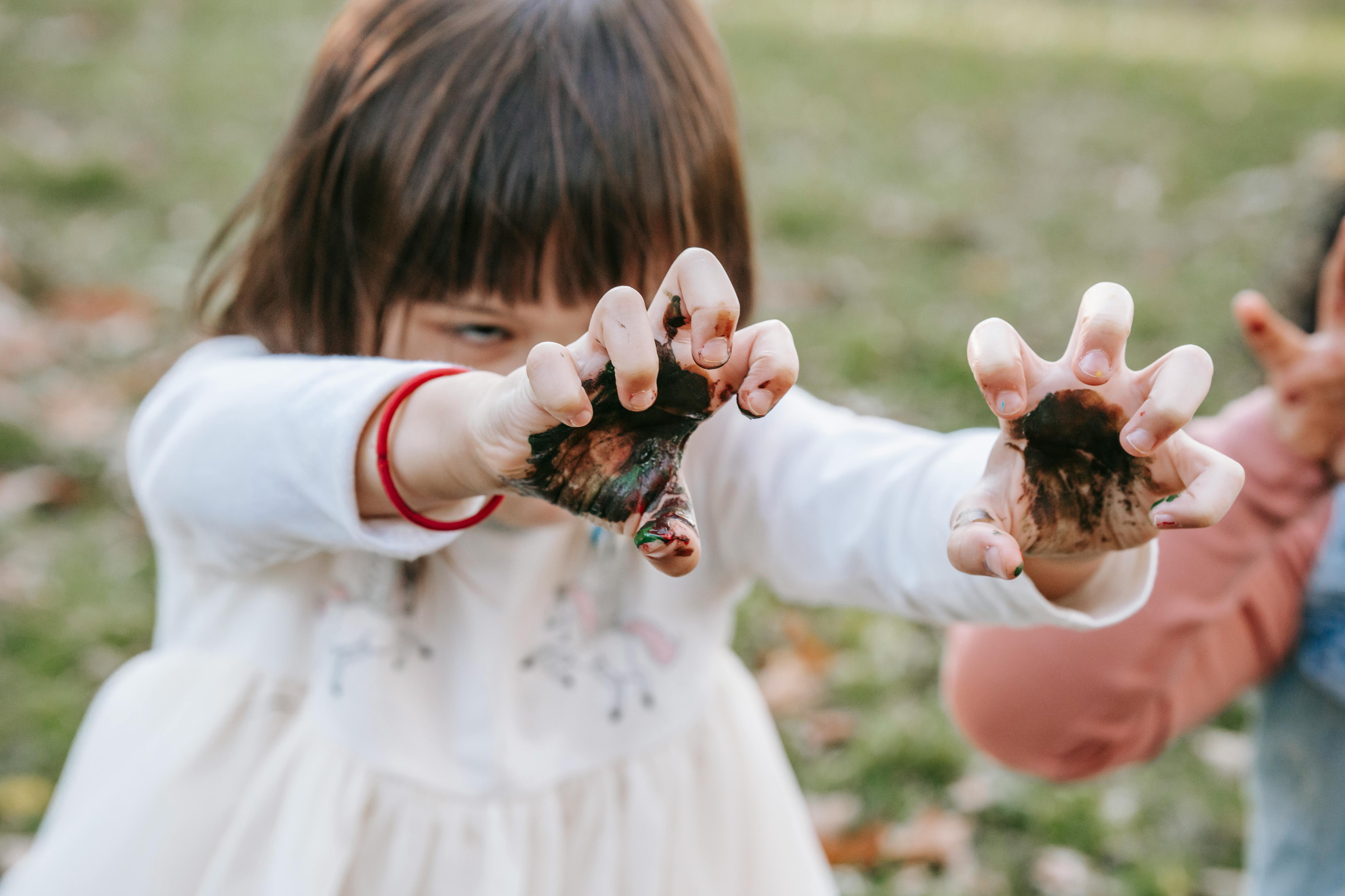 children with painted hands playing in park