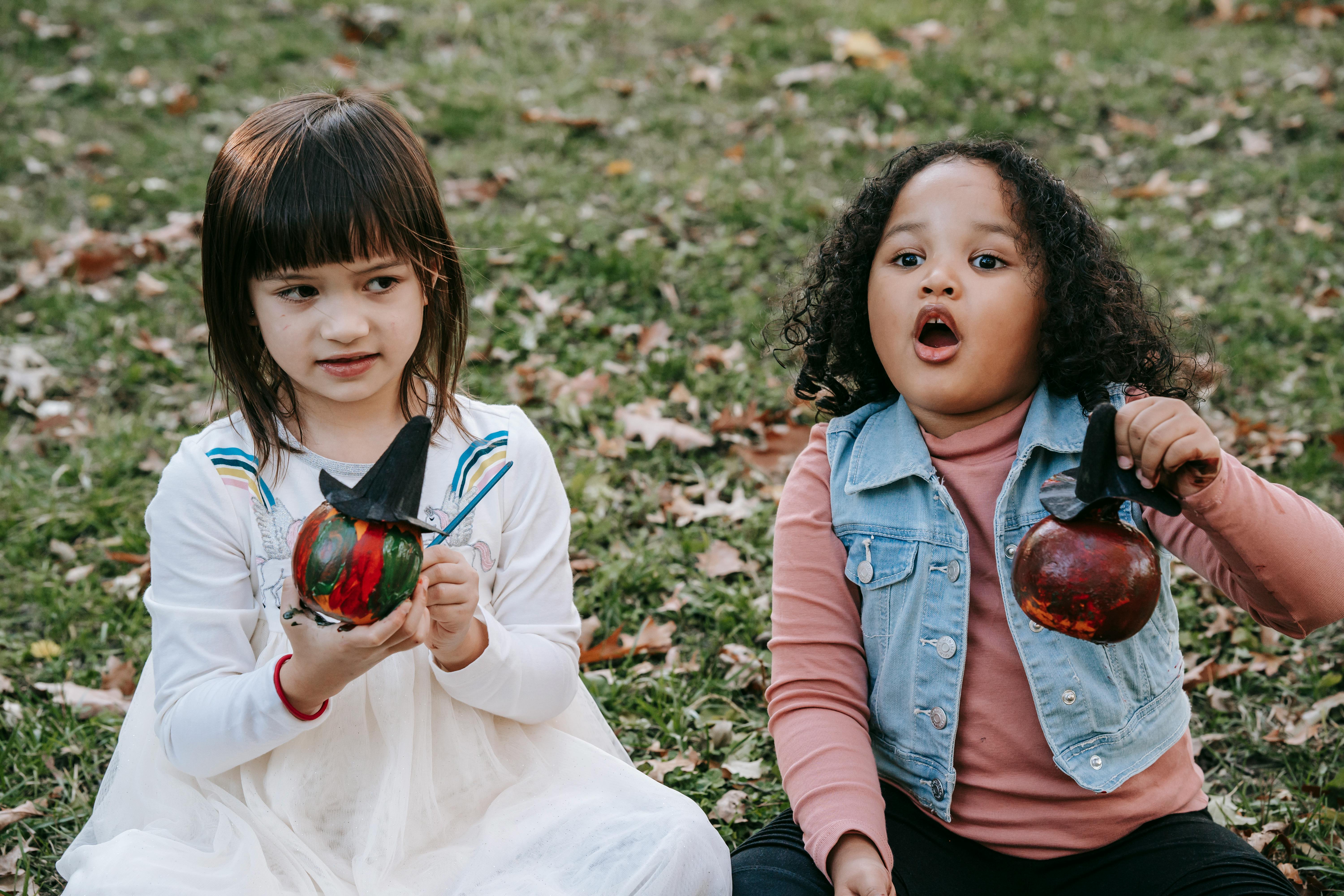 cute diverse little girls with painted halloween pumpkins