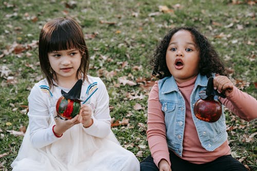 Cute diverse little girls with painted Halloween pumpkins