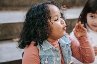 Side view of adorable little African American girl in casual clothes making faces
