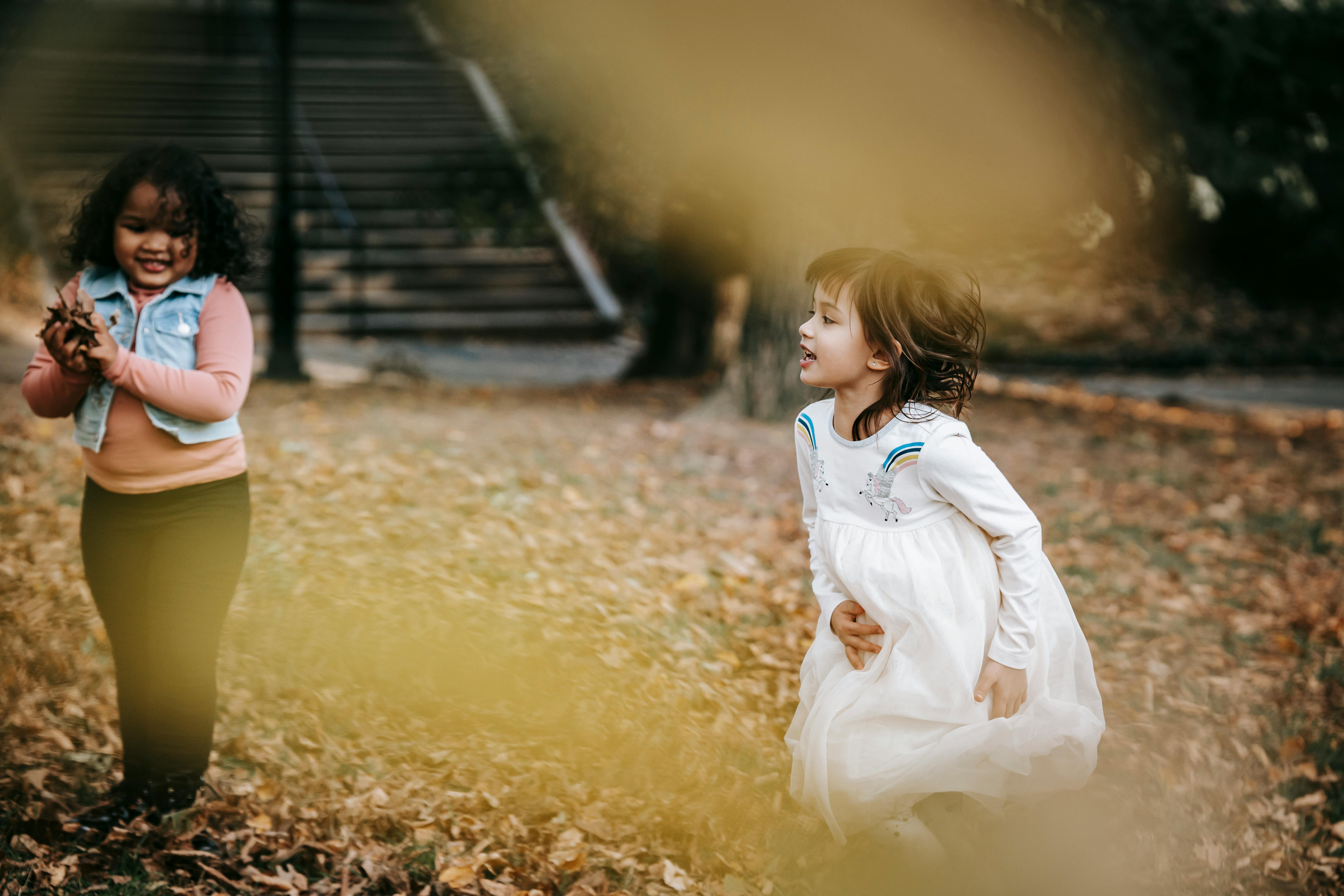 happy multiracial girls playing with leaves