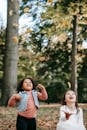 Happy multiracial girls having fun while playing with fallen leaves in autumn park