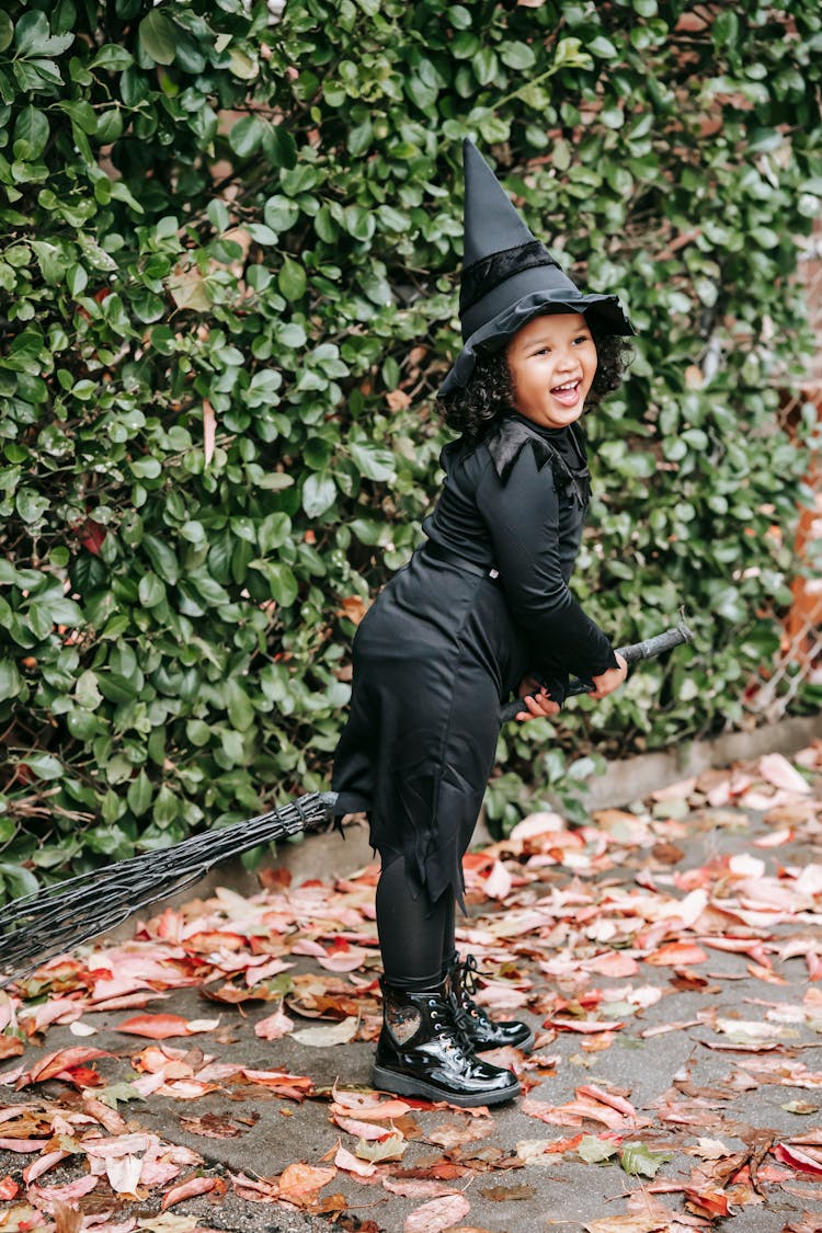 Funny Girl In Witch Costume Near Shrub