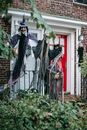 Terrible scarecrows of witch and skeletons on fence near entrance of brick building