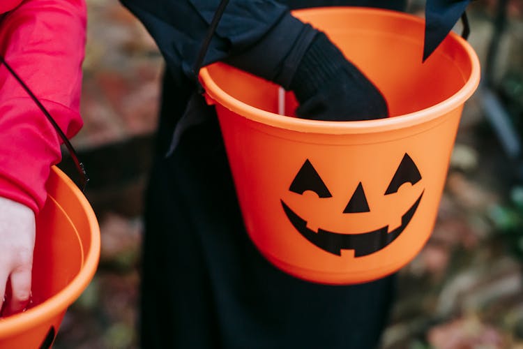 Crop Kids Folding Treats In Bucket On Halloween