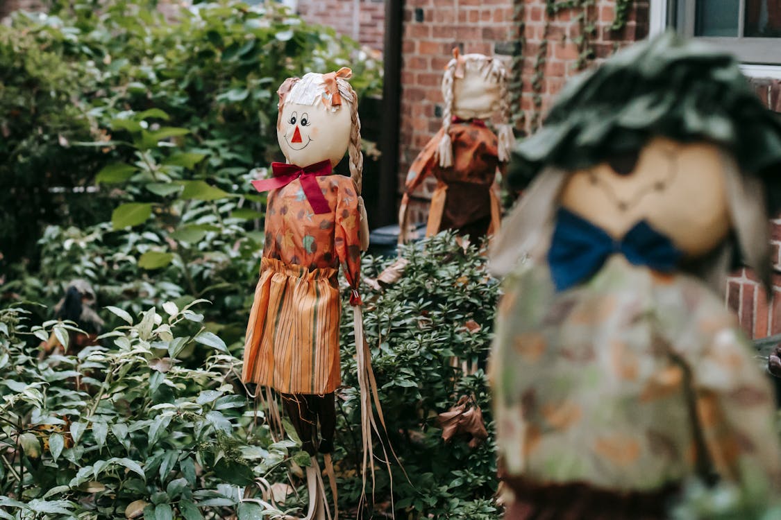 Free Terrible figurines of fictional characters near entrance of brick building with lush vegetation on Halloween Stock Photo