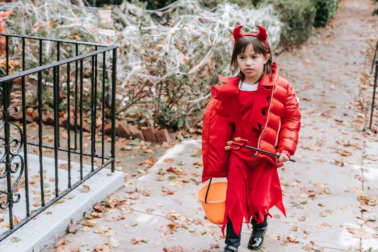 Little Kid Trick Or Treating In Street In Devil Costume