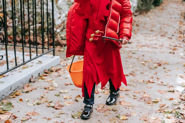 Unrecognizable Kid In Devil Costume Walking With Bucket On Halloween