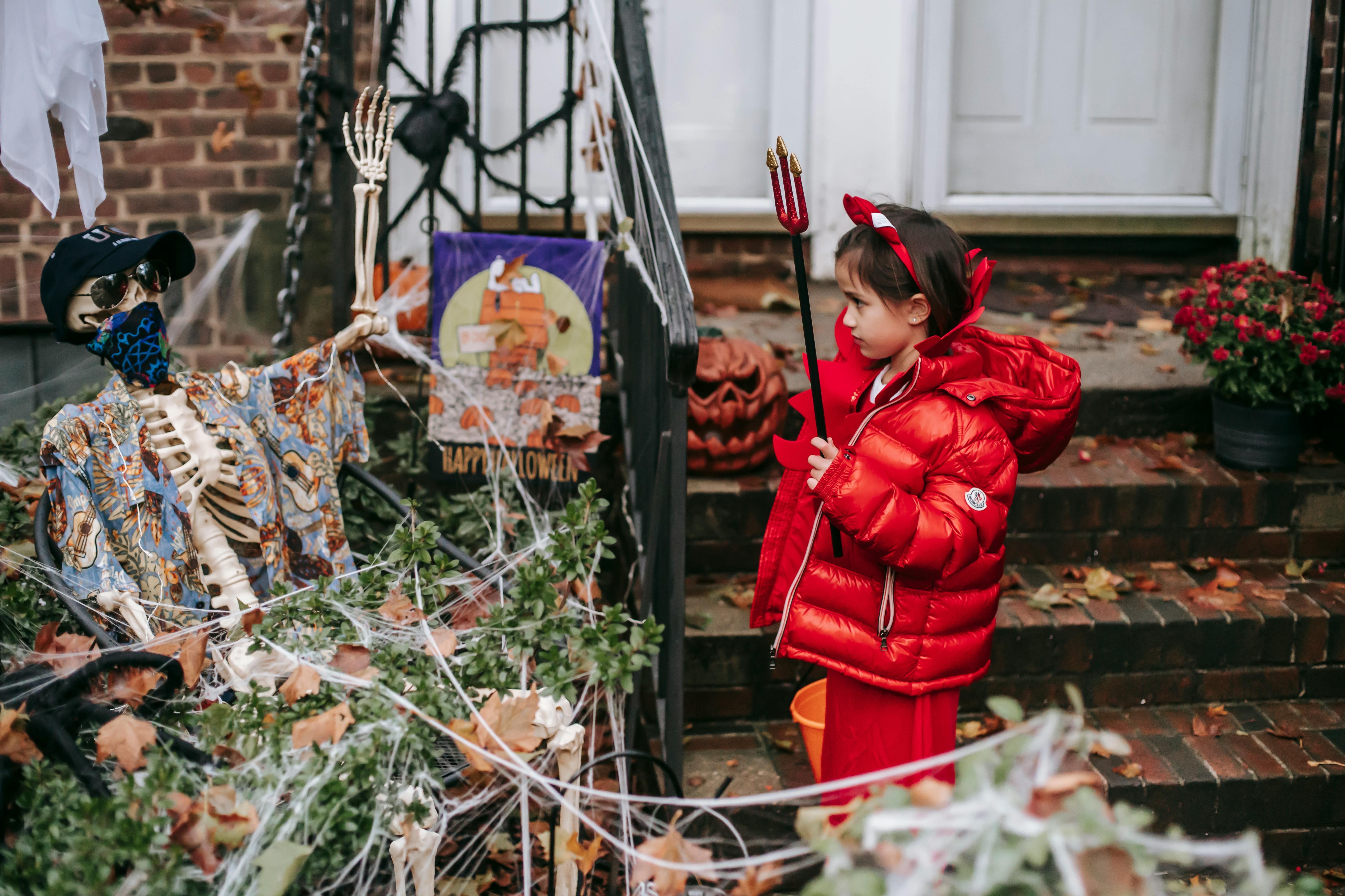 little girl in devil costume on halloween near house