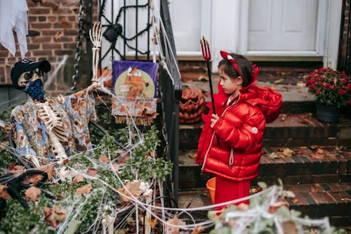 Little girl in devil costume on Halloween near house