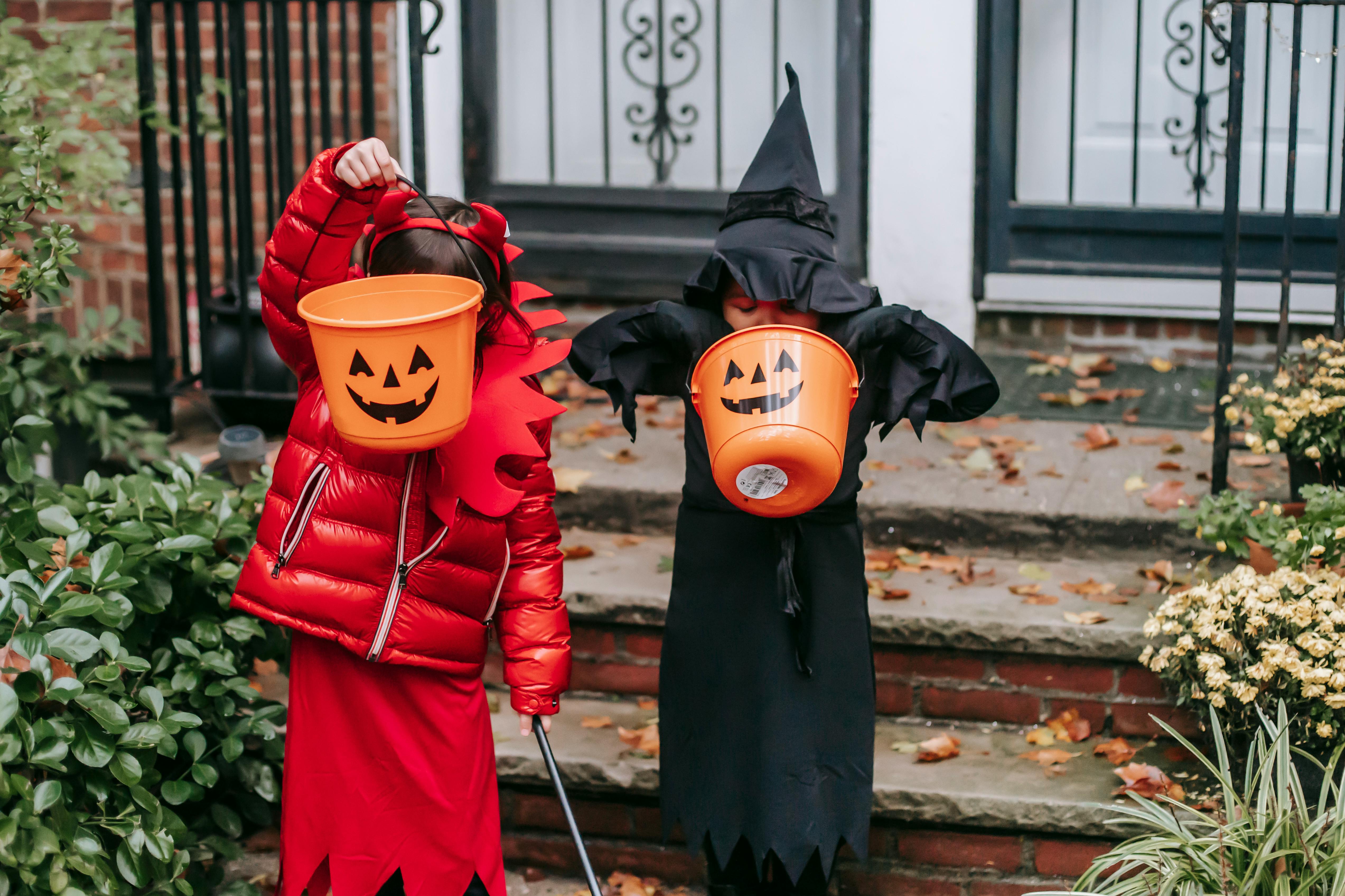 faceless kids strolling on halloween in witch and devil costume