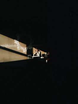 A woman sits in shadow and light, surrounded by conceptual digital elements, creating a striking visual contrast.