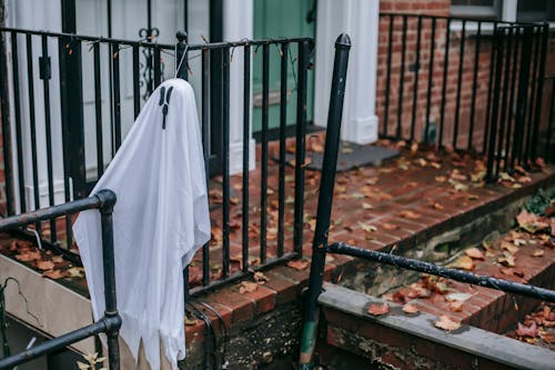 White ghost hanging on railing of porch