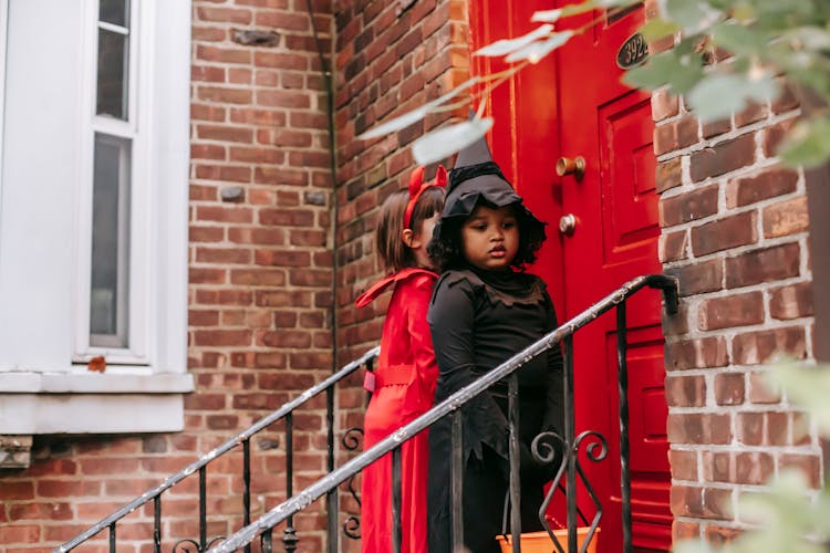 Kids In Halloween Costumes Standing Outside House