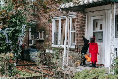 Little kids in fancy Halloween costumes outside house