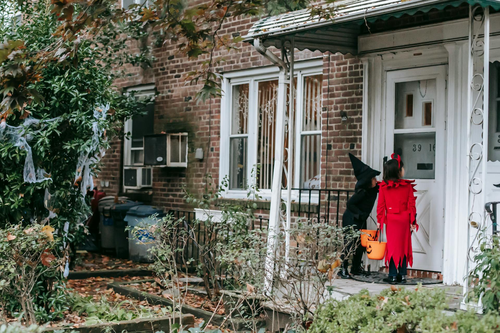 Little kids in fancy Halloween costumes outside house