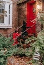 Side view of anonymous children wearing witch and devil costumes walking upstairs at entrance of brick house while celebrating holiday