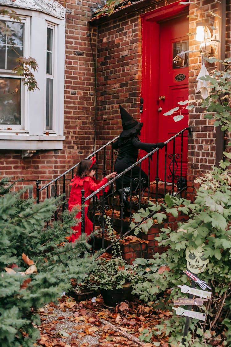 Unrecognizable Kids In Halloween Costumes Walking Up Stairs On Porch